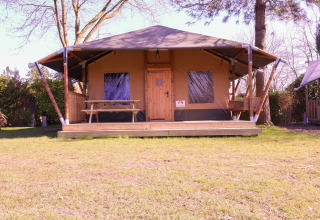 Tienda safari Cottage Kaa en Camping Vossenberg, Países Bajos, con terraza de madera y mesa de picnic.