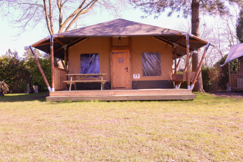 Tenda safari Cottage Kaa presso Camping Vossenberg nei Paesi Bassi con veranda in legno e tavolo da picnic.