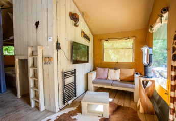 Indvendigt af Safari telt Cottage Kaa på Camping Vossenberg, Holland, hyggefuldt med sofa og trædetaljer.