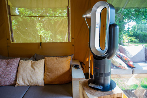 Sala de estar en la tienda Safari Cottage Kaa con ventilador moderno y cojines en Camping Vossenberg, Países Bajos.
