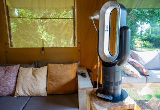 Sala de estar en la tienda Safari Cottage Kaa con ventilador moderno y cojines en Camping Vossenberg, Países Bajos.
