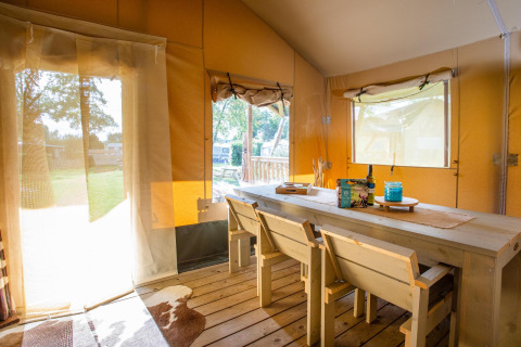 Interior de la tienda Safari Cottage Kaa en Camping Vossenberg, Países Bajos, con muebles de madera clara.