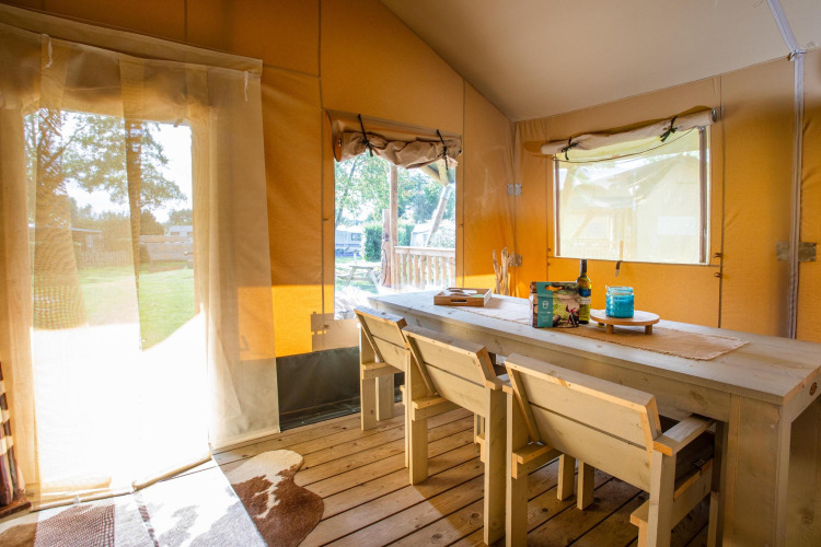 Interior of Safari tent Cottage Kaa at Camping Vossenberg in the Netherlands, featuring wood furniture.