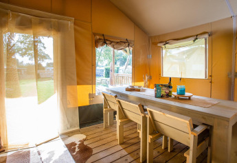Innenaufnahme des Safari-Zelts Cottage Kaa auf Camping Vossenberg in den Niederlanden, mit Holzmöbeln.