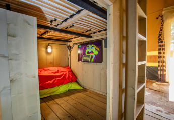 Innenaufnahme des Safari-Zelts Cottage Kaa auf dem Camping Vossenberg in den Niederlanden mit Bett und TV.