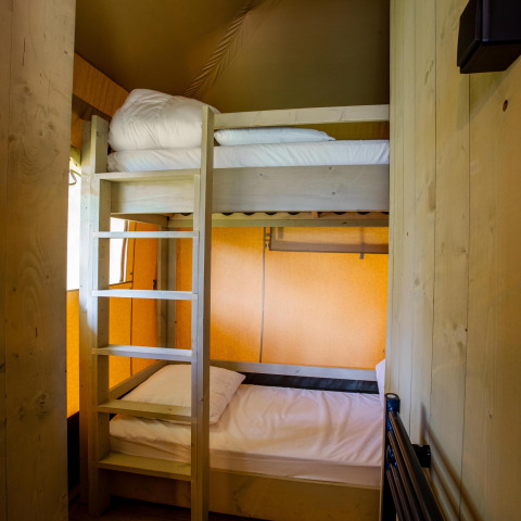 Dormitorio con litera y decoración de madera en la tienda Safari Cottage Kaa de Camping Vossenberg, Países Bajos.