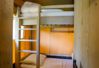 Dormitorio con litera y decoración de madera en la tienda Safari Cottage Kaa de Camping Vossenberg, Países Bajos.