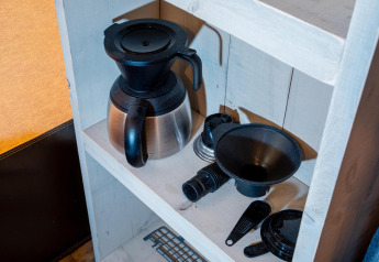 Kaffemaskine og tilbehør på en hvid hylde i Safari tent Cottage Kaa på Camping Vossenberg i Holland.