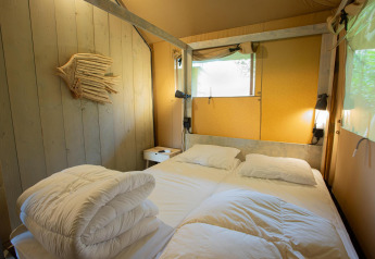 Soveværelse i Safari tent Cottage Kaa med dobbeltseng, trævæg og vindue på Camping Vossenberg i Holland.