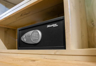 Caja fuerte Master Lock en una estantería de madera en Safari tent Cottage Kaa en Camping Vossenberg, Países Bajos.