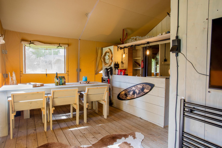 Interior de la tienda Safari Cottage Kaa en Camping Vossenberg, Países Bajos, con decoración rústica.