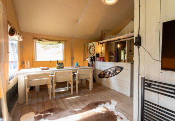 Interiør af Safari telt Cottage Kaa på Camping Vossenberg i Holland med træbord, stole og rustik indretning.