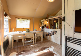 Interior de Safari tent Cottage Kaa en Camping Vossenberg, Países Bajos, con decoración rústica y comedor.