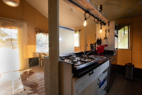 Cocina dentro de la Safari tent Cottage Kaa en Camping Vossenberg, Países Bajos, con estufa y decoración moderna.