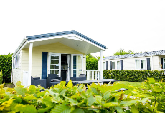 Delta Lodge at Holiday Park Duinhoeve in the Netherlands with patio seating, greenery, and a modern look.