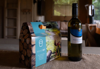 Botella de vino y set de servicio sobre mesa en Safari tent Cottage Kaa, Camping Vossenberg, Países Bajos.