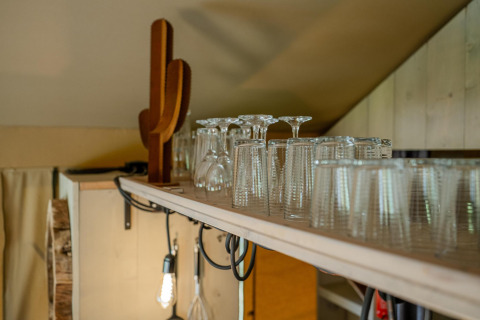 Estante con vasos y decoración en Safari tent Cottage Kaa en Camping Vossenberg, Países Bajos.