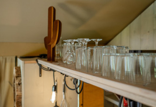 Estante con vasos y decoración en Safari tent Cottage Kaa en Camping Vossenberg, Países Bajos.