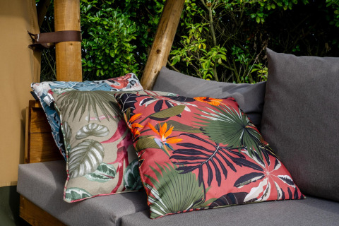 Cojines decorativos con estampado tropical en un sofá gris del Safari tent Cottage Kaa en Camping Vossenberg, Holanda.