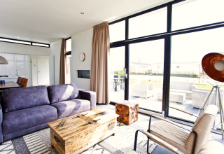 Salon moderne à L-Cube 6 à Schoneveld, Pays-Bas, avec grandes fenêtres et mobilier contemporain.