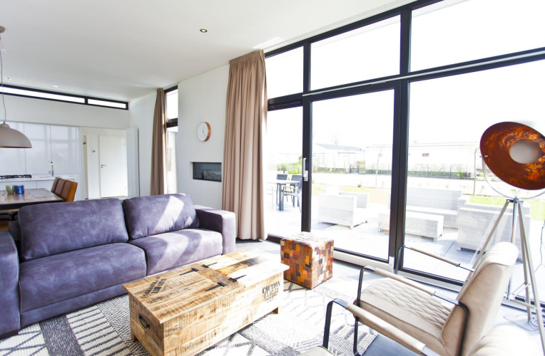 Sala moderna en L-Cube 6 en Schoneveld, Países Bajos, con grandes ventanales y muebles contemporáneos.