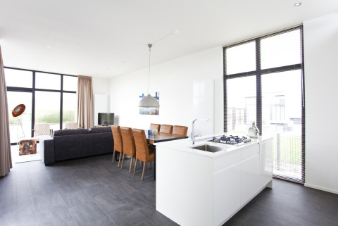 Helles, modernes Wohnzimmer und Küche in der L-Cube 6 Lodge Schoneveld, Niederlande, mit großen Fenstern.