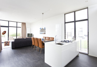 Helles, modernes Wohnzimmer und Küche in der L-Cube 6 Lodge Schoneveld, Niederlande, mit großen Fenstern.