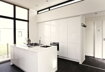 Moderne, minimalistisk køkken i L-Cube 6 på Schoneveld, Holland, med hvide skabe og store vinduer.