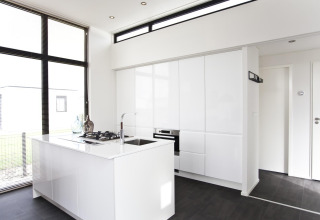 Cocina moderna minimalista en L-Cube 6 de Schoneveld, Países Bajos, con gabinetes blancos y gran ventanal.