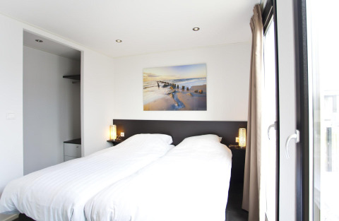 Moderne slaapkamer in L-Cube 6 in Schoneveld, Nederland, met tweepersoonsbed en grote ramen.