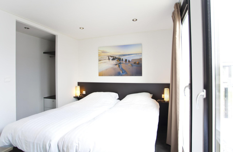 Dormitorio moderno en L-Cube 6 en Schoneveld, Países Bajos, con cama doble y gran ventanal.