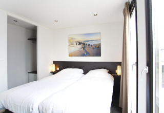 Dormitorio moderno en L-Cube 6 en Schoneveld, Países Bajos, con cama doble y gran ventanal.