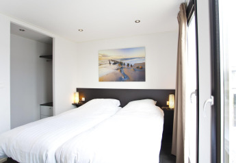 Dormitorio moderno en L-Cube 6 en Schoneveld, Países Bajos, con cama doble y gran ventanal.