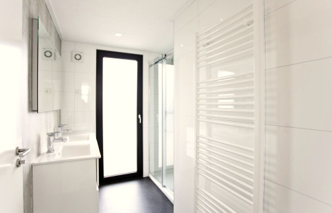 Salle de bain moderne du L-Cube 6 à Schoneveld, Pays-Bas, avec douche, porte vitrée et sèche-serviettes.