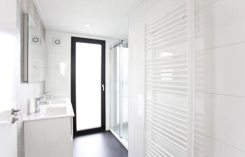 Salle de bain moderne du L-Cube 6 à Schoneveld, Pays-Bas, avec douche, porte vitrée et sèche-serviettes.