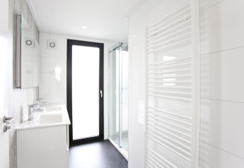 Modern ingerichte badkamer in L-Cube 6, Schoneveld, Nederland met douchecabine, handdoekradiator en deur.