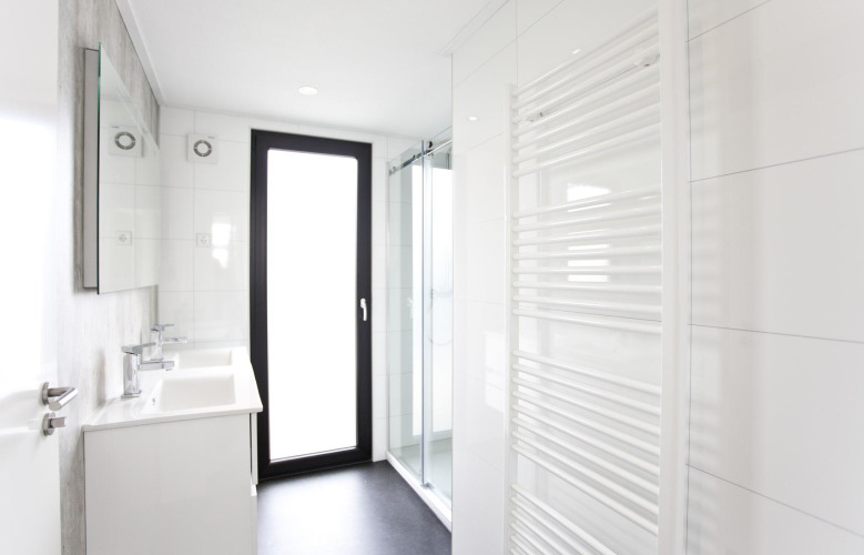 Baño moderno en L-Cube 6, Schoneveld, Países Bajos, con ducha acristalada y radiador toallero blanco.