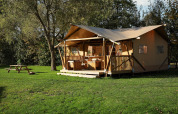 Tienda de glamping La Vida en Resort de Parel, Países Bajos, con porche y mesa de picnic sobre césped verde.