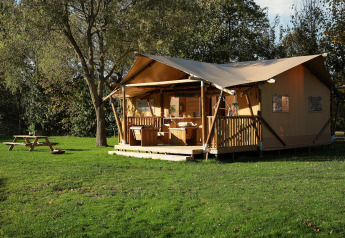 Safari-Glampingzelt La Vida im Resort de Parel, Niederlande, mit Veranda und Picknicktisch im Grünen.