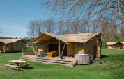 Glamping-Safari-Zelt La Gran Vida im Resort de Parel, Niederlande, mit Holzterrasse und Whirlpool.