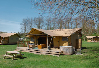 Glamping-Safari-Zelt La Gran Vida im Resort de Parel, Niederlande, mit Holzterrasse und Whirlpool.
