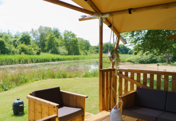 Blick von einem Glamping-Zelt La Gran Vida im Resort de Parel, Niederlande auf Terrasse und Teich.