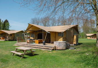 Glamping-Zelt La Gran Vida im Resort de Parel, Niederlande, mit Terrasse, Holztisch und Whirlpool.