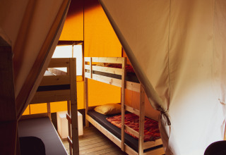 Interior of a safari tent at Rhederlaagse Meren, Netherlands, featuring wooden bunk beds and orange walls.