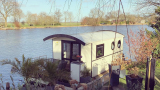Husbåd ved Rhederlaagse Meren rekreative park i Holland, omgivet af natur og vand med udsigt over søen.
