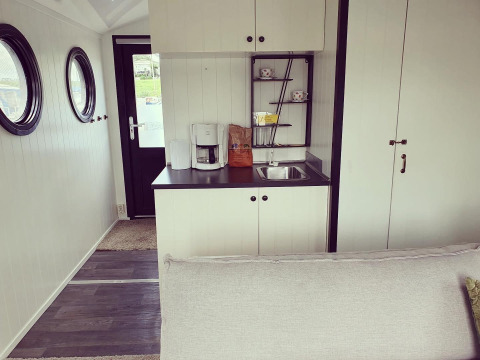 Cocina de casa flotante en Rhederlaagse Meren, Países Bajos, con cafetera, fregadero y ventanas redondas.