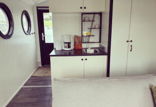 Keuken van een woonboot bij Rhederlaagse Meren met koffiemachine, gootsteen en ronde ramen.