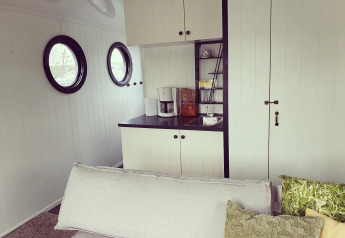 Acogedora sala y cocina en una casa flotante en Rhederlaagse Meren, Países Bajos, con ventanas redondas.