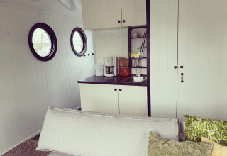 Accogliente soggiorno e angolo cottura su una houseboat a Rhederlaagse Meren, Olanda, con finestre tonde.