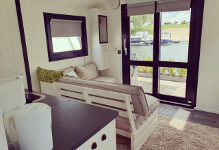 Interno di una houseboat al Rhederlaagse Meren, Paesi Bassi, con vista sul porto turistico dalle vetrate.
